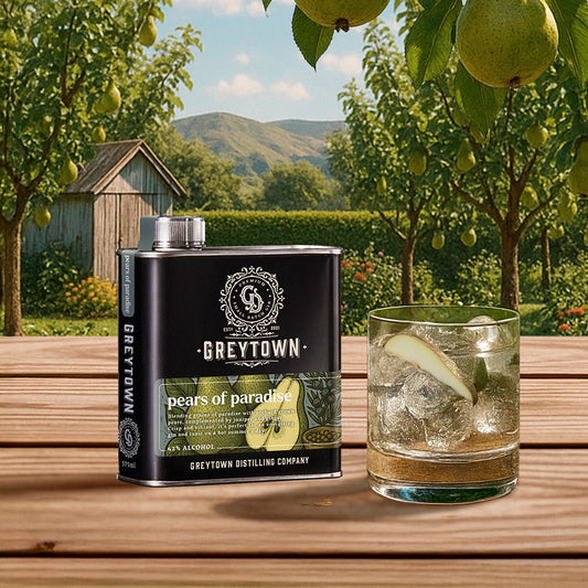 Black flask of Greytown Distilling Co, New Zealand 'Pears of Paradise' gin with a glass of gin on a wooden table outdoors.